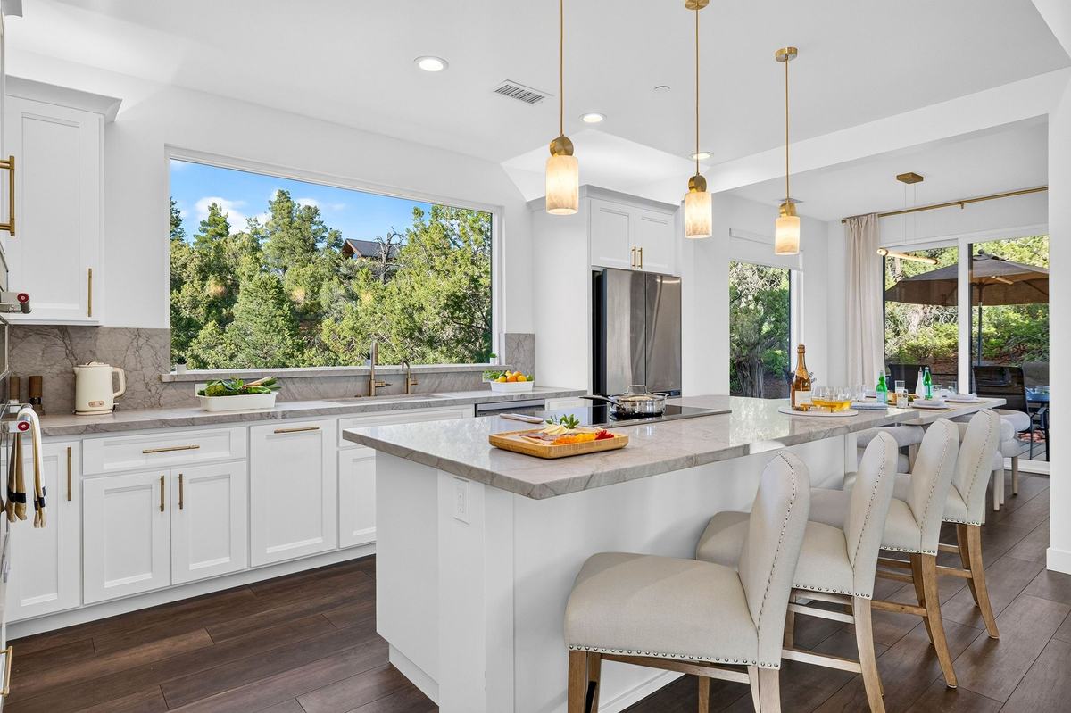 Kitchen with white cabinets, a long island, and bar stools.