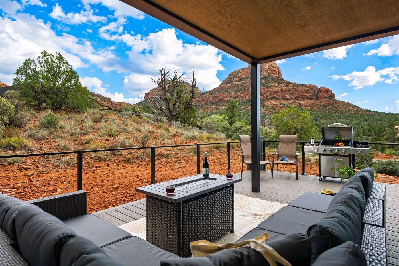 The covered deck with a sectional and fire table, looking out to Twin Buttes under a blue sky.