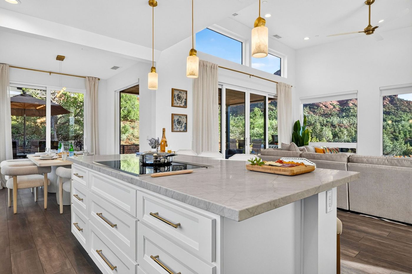 The kitchen island with pendant lights, open to the dining table and living room, with red rocks through the windows.